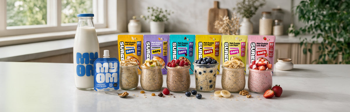 Six oat pots of SURREAL Overnight Oats in Chocolate, Salted Caramel, Peanut Butter, Honey, Banana and Strawberry flavours, displayed with MYOM Original Oat Drink.