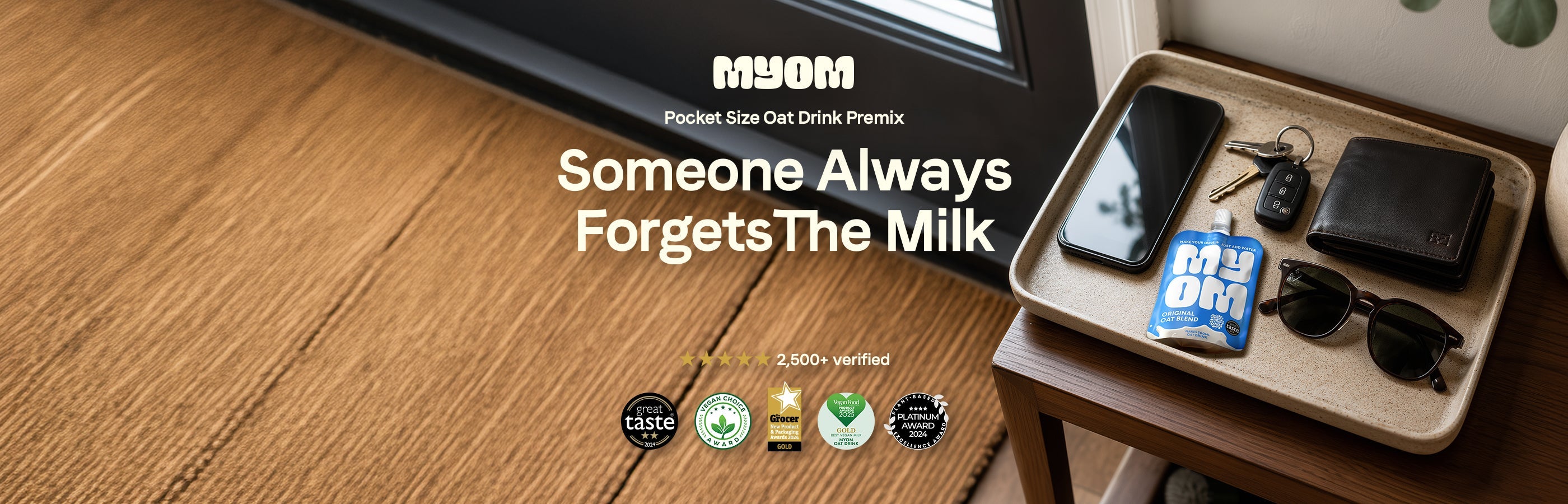 MYOM Original Oat Anywhere pouch in a tray of valuables including a phone, keys and wallet by a front door inside a house — Someone always forgets the milk.