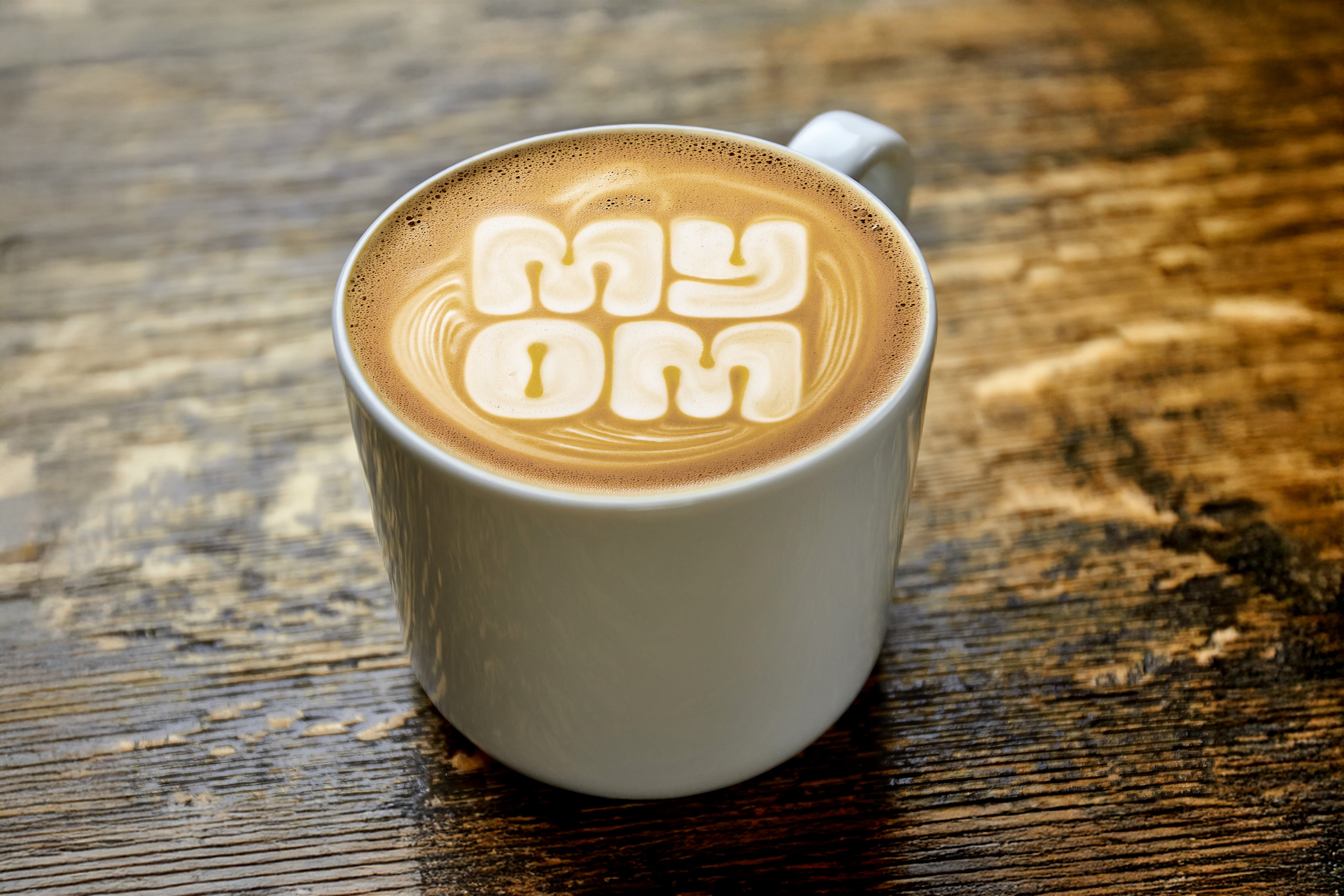Flat white coffee with MYOM logo latte art created using glossy oat milk microfoam.