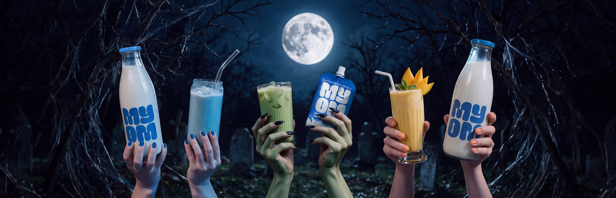 Hands holding green, blue and mango Halloween drinks, MYOM bottles and a MYOM Original Oat Drink Premix pouch beneath a full moon.