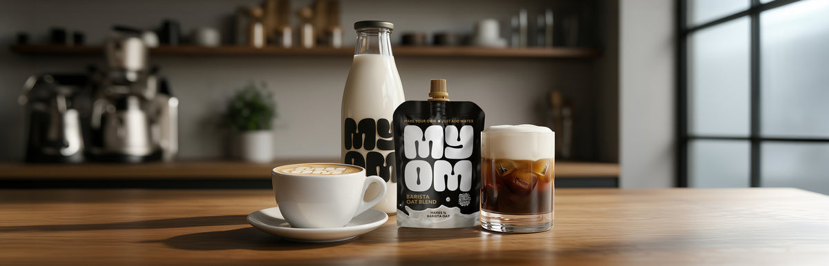 MYOM Barista oat milk in a cappuccino with latte art beside an iced cold brew topped with cold foam, the premix pouch and 1L glass bottle behind