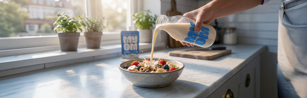 MYOM oat milk poured from a glass bottle over cereal topped with strawberries, blueberries and banana.